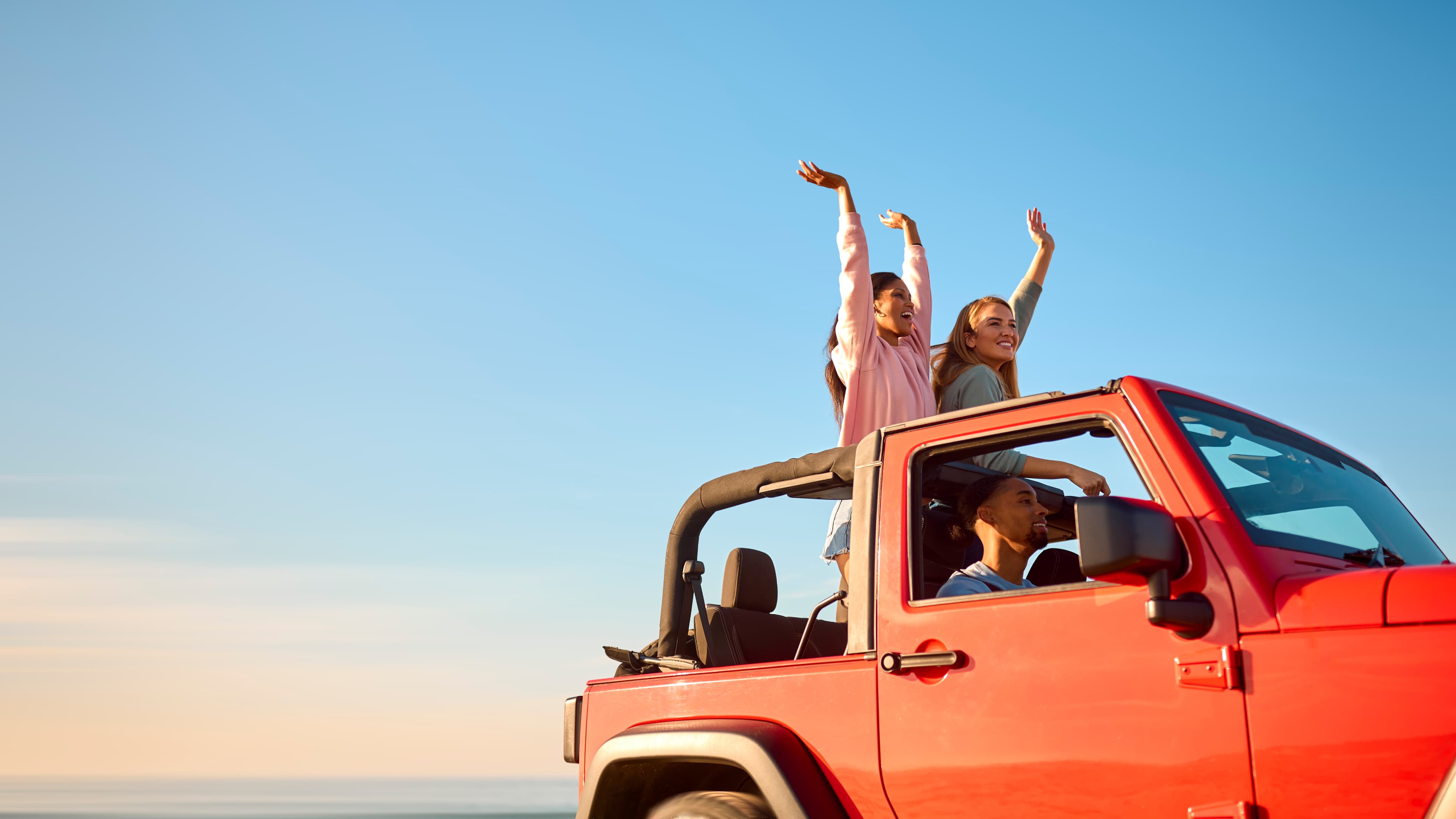 Passagers dans un SUV décapotable sous un ciel bleu